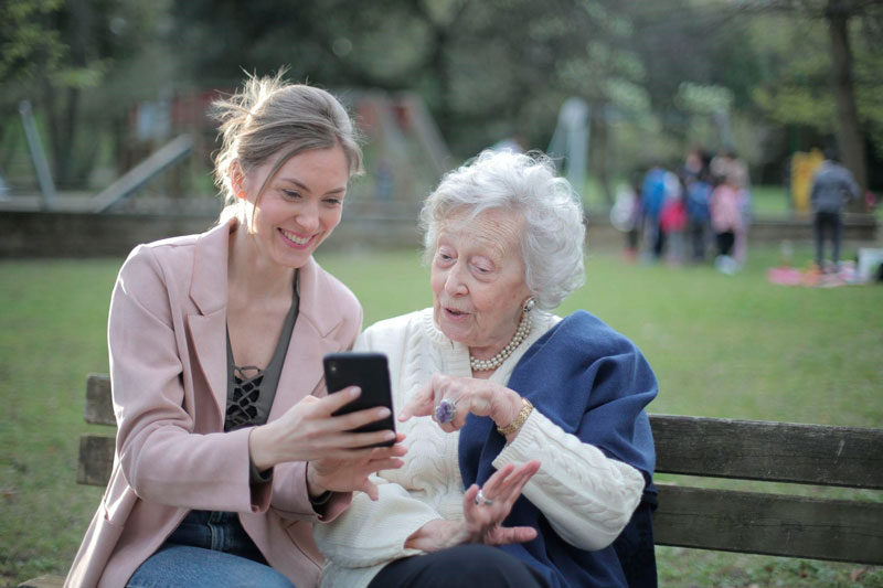 Mujer joven enseñandole fotos a una mujer mayor con un celular