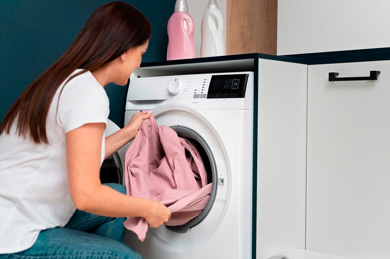 Mujer retirando la ropa de un lavarropas