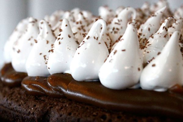 Torta de chocolate decorada con copos de merengue italiano firme y brillante
