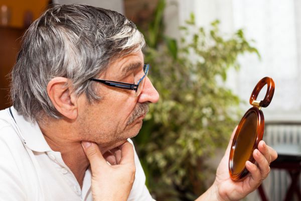 Persona de la tercera edad observando su doble mentón. Se puede reducir con ejercicios simples.