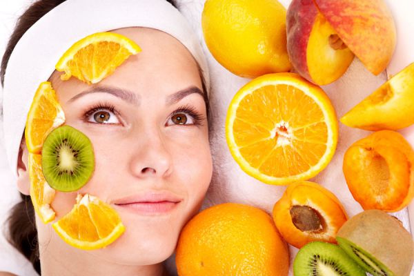 Rostro de mujer con trozos de naranjas, ingrediente para hacer mascarillas naturales para la piel