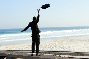 Hombre tirando el maletín en la playa tras abandonar su empleo.